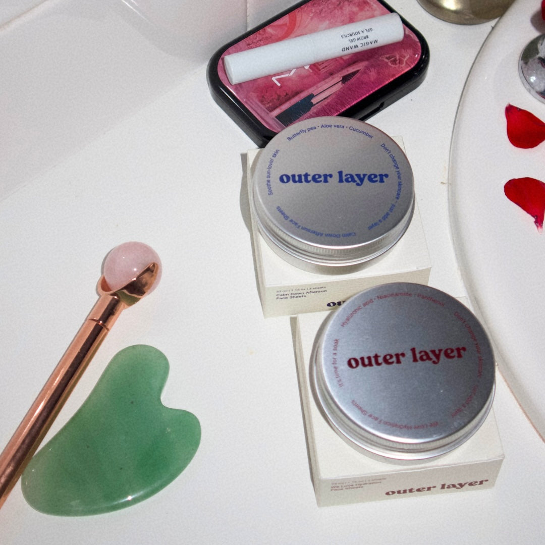 Outer Layer tins and beauty tools on white countertop