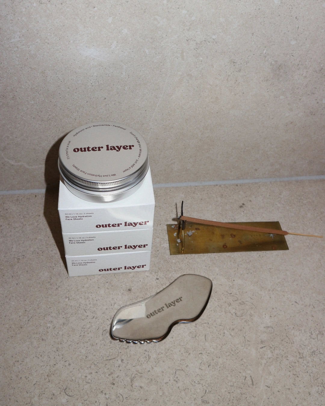 Cosmetic products with 'Outer Layer Face Sheet Masks' branding on a neutral background